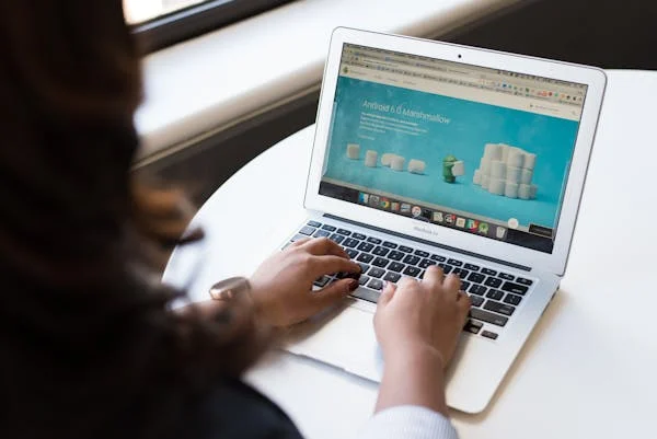 a woman has her hands on laptop open in front of her on a white table